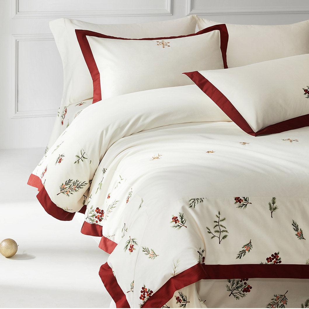 White bedding set with red trim and floral patterns on a white background