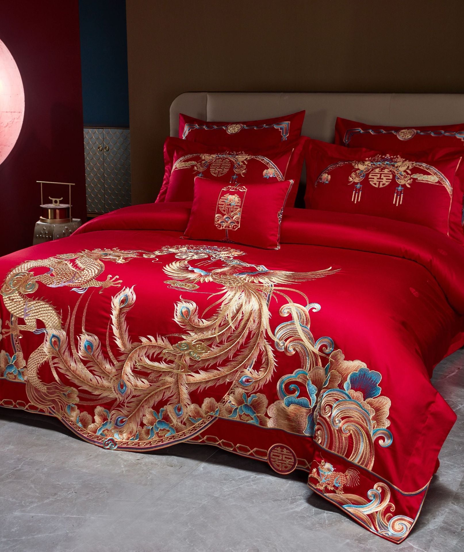 Red embroidered Chinese Dragon bedding set with intricate designs on a bed in a dimly lit room.