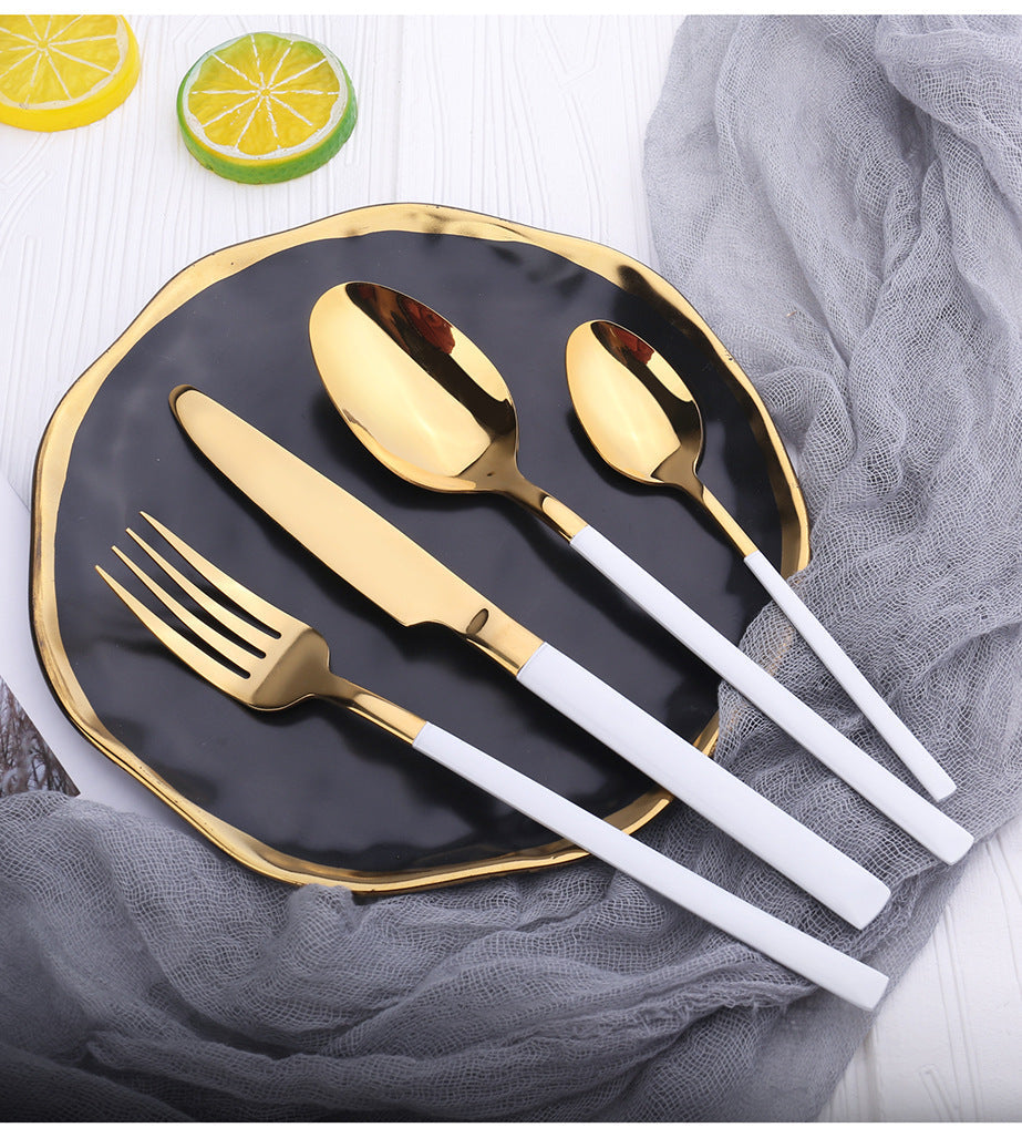 Gold cutlery set on a black plate with lemon slices in the background