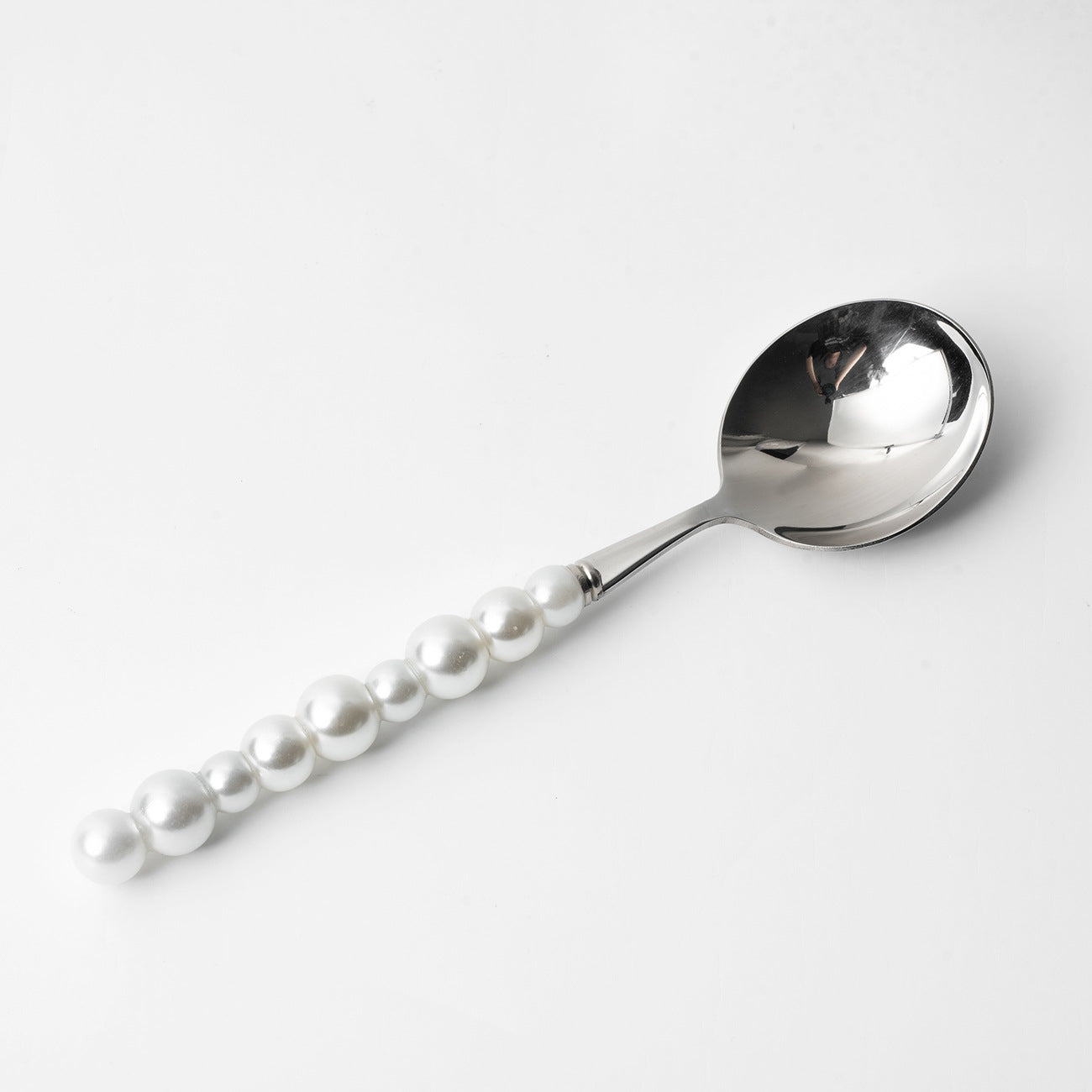 Spoon with pearl handle on a white background