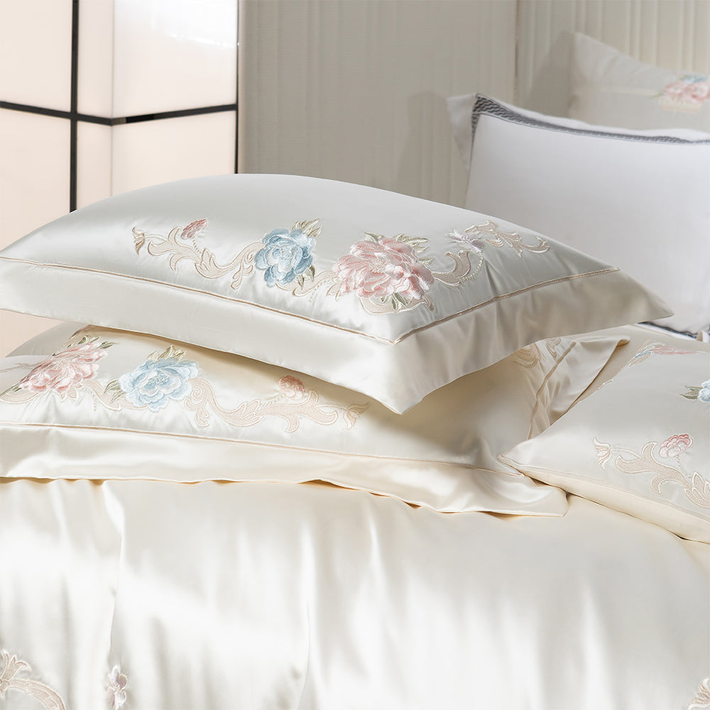 Embroidered pillows with floral designs on a bed