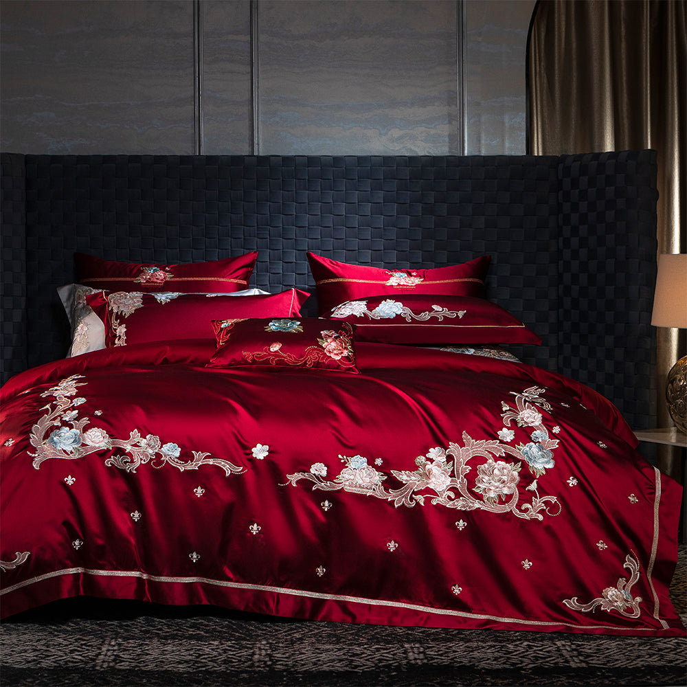 Red embroidered bedding set on a bed with a dark headboard.