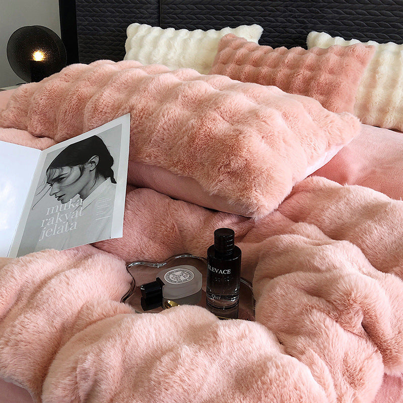 Pink faux rabbit fur bedding with a book and small bottle on a bed