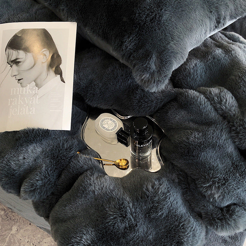 Dark gray faux rabbit fur bedding with a perfume bottle, small mirror, and book on top