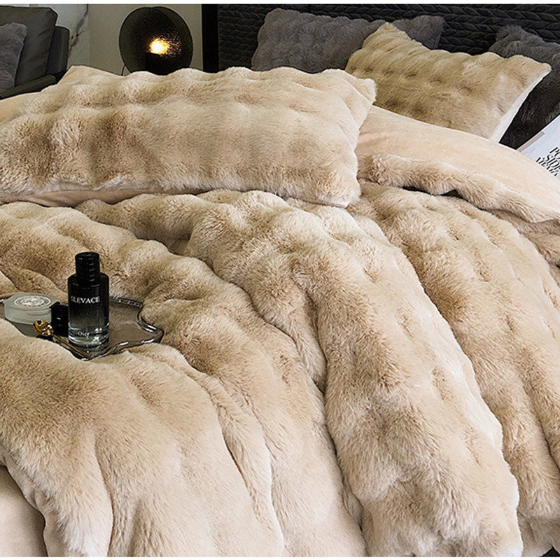 Beige faux fur blanket on a bed with a tray and bottle of cologne.