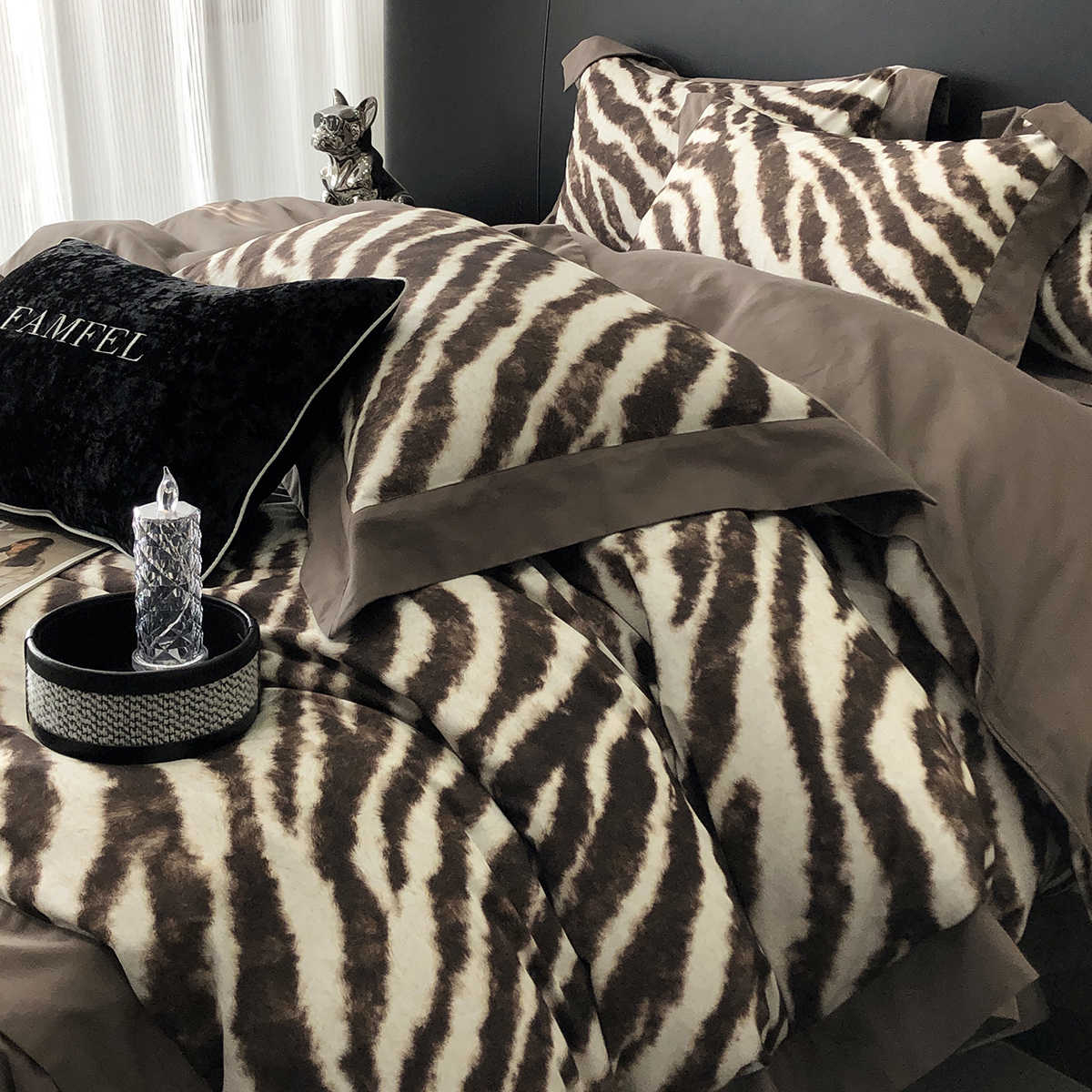 Bed with zebra print bedding and decorative pillows in a bedroom setting.