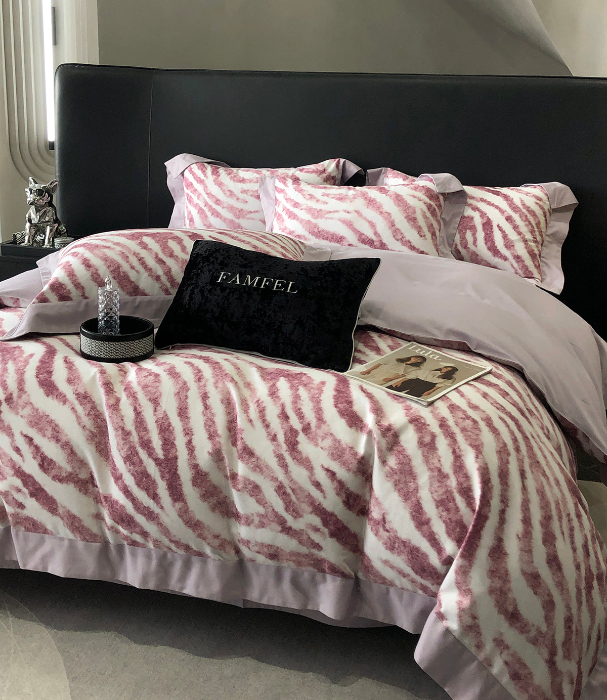 Bed with pink and white zebra pattern bedding, black headboard, and decorative items.