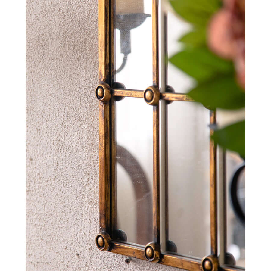 Decorative window pane wall mirror with gold frame on a textured wall
