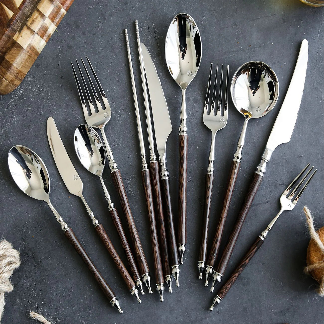 Silver cutlery set with brown handles on a dark surface