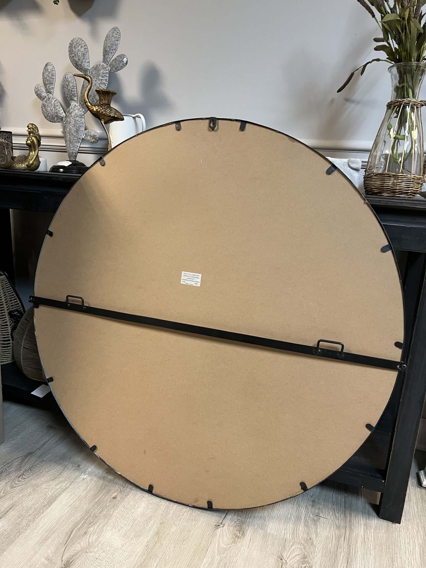 Large round beige mat with black border on a wooden floor