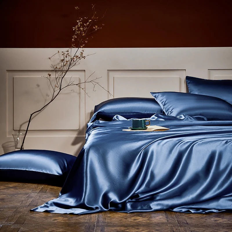 Blue satin bedding set on a bed with a minimalistic headboard.