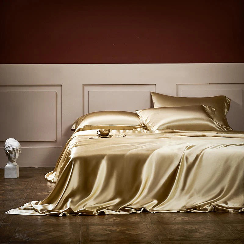 Gold satin bedding set on a bed in a bedroom with a dark red wall.