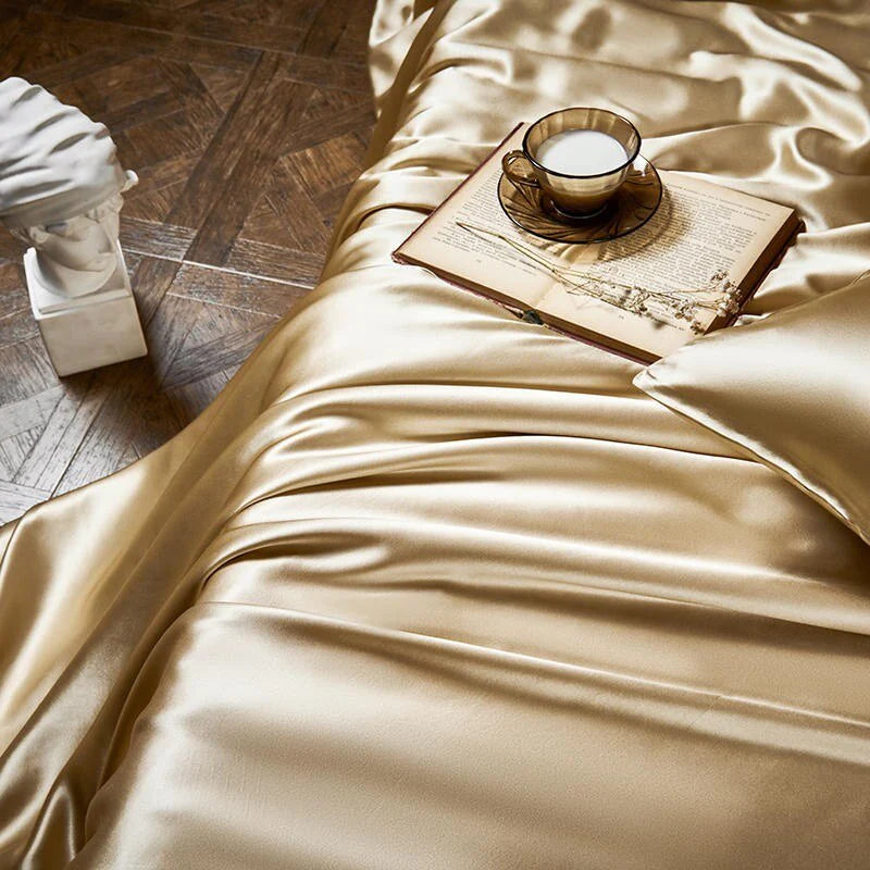 Beige satin fabric with a cup and saucer on an open book, next to a classical statue.