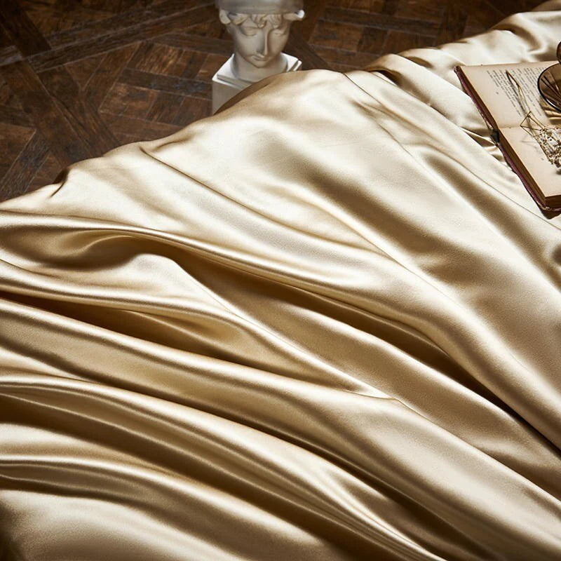 Beige satin fabric draped over a surface with a classical statue and book in the background.