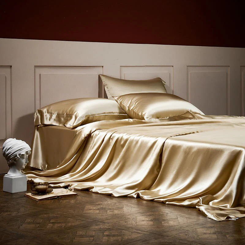 Gold satin bedding set on a bed with classical sculpture in the foreground.