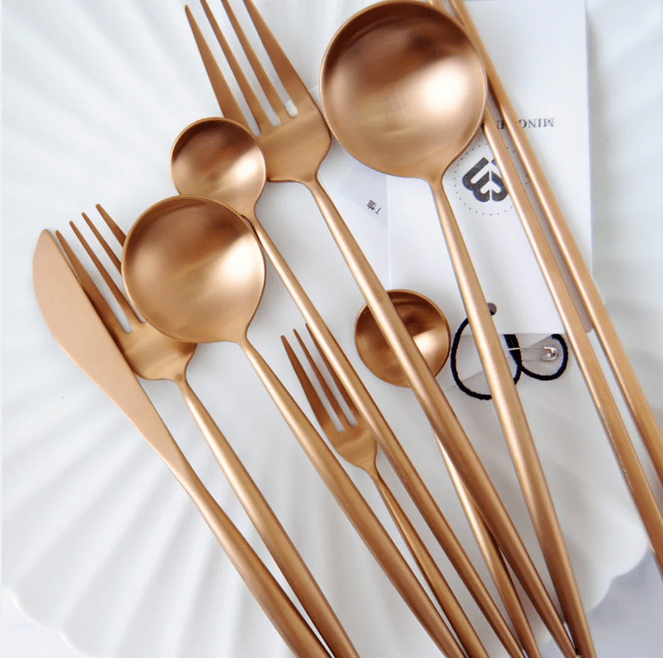 Rose gold cutlery set on a white surface