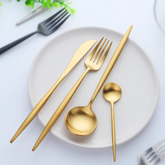 Gold cutlery set on a white plate with a white background