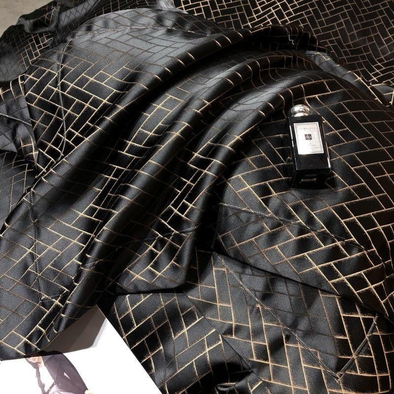 Black textured fabric with a geometric pattern and a small bottle on top.