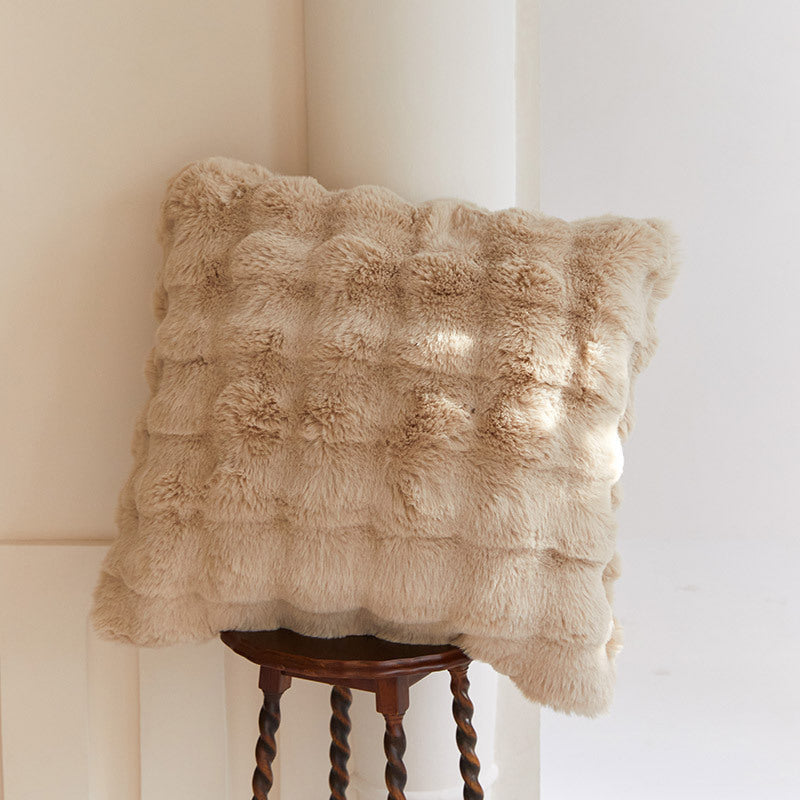 Textured beige pillow on a wooden stool against a neutral wall