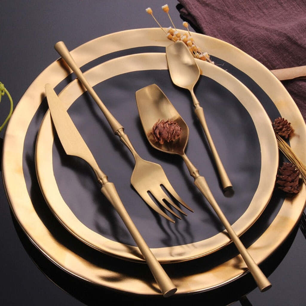 Gold cutlery set on a dark surface with decorative elements.