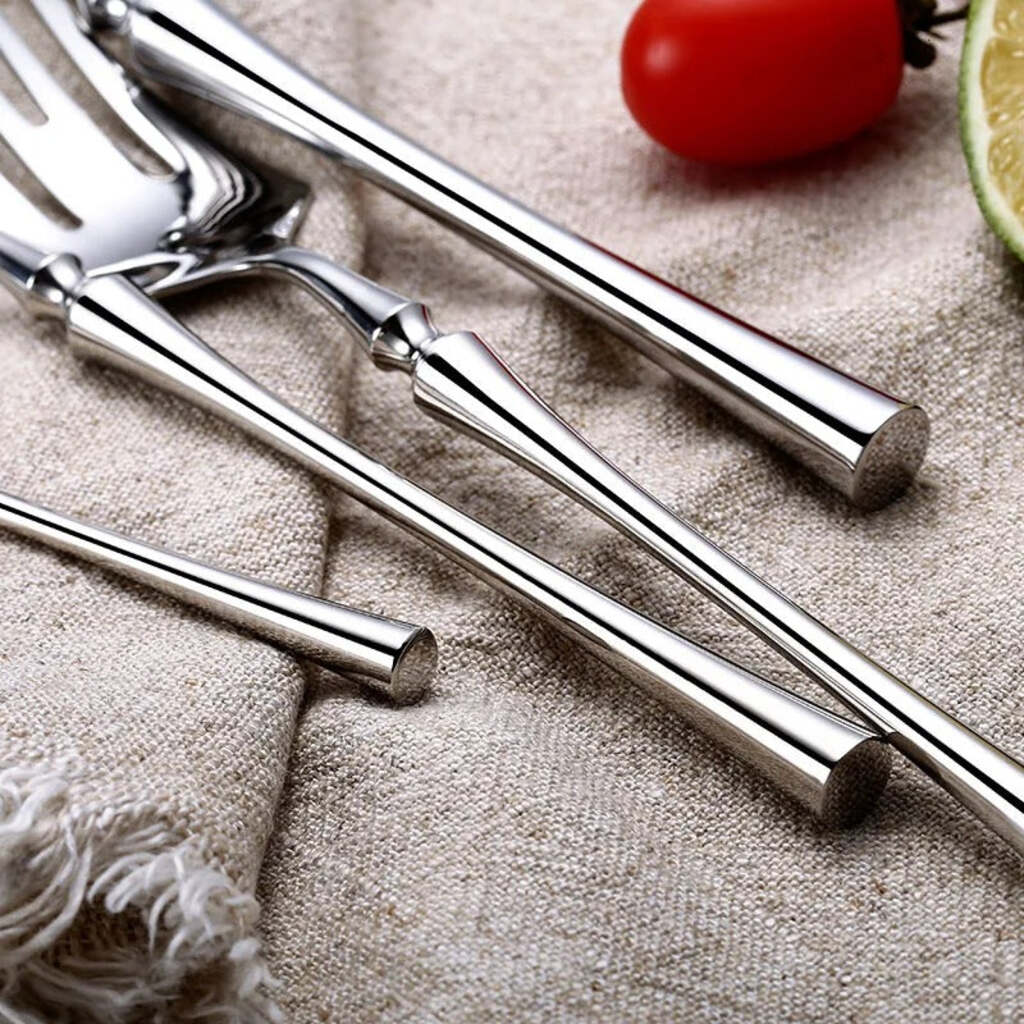 Set of metal straws on a textured surface with a tomato and lime in the background.