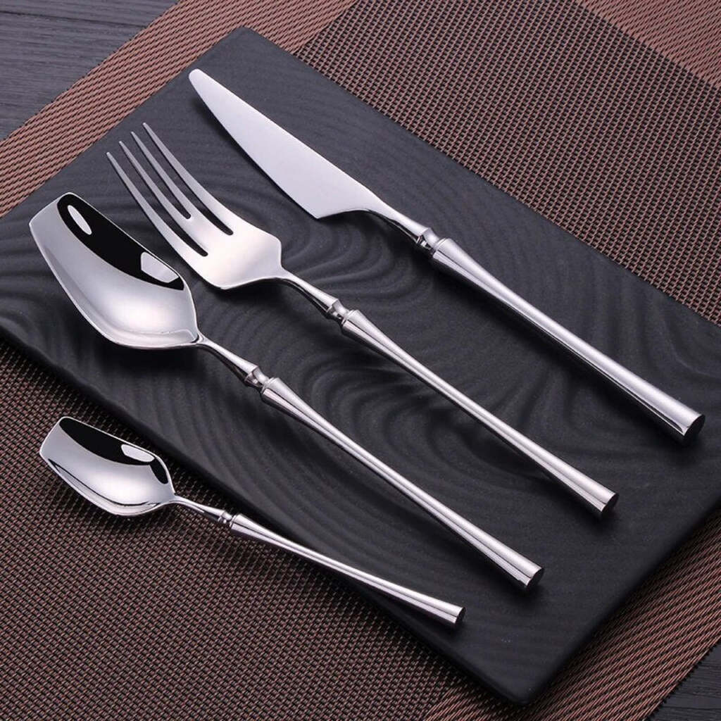 Set of silver cutlery including a knife, fork, and two spoons on a dark surface.