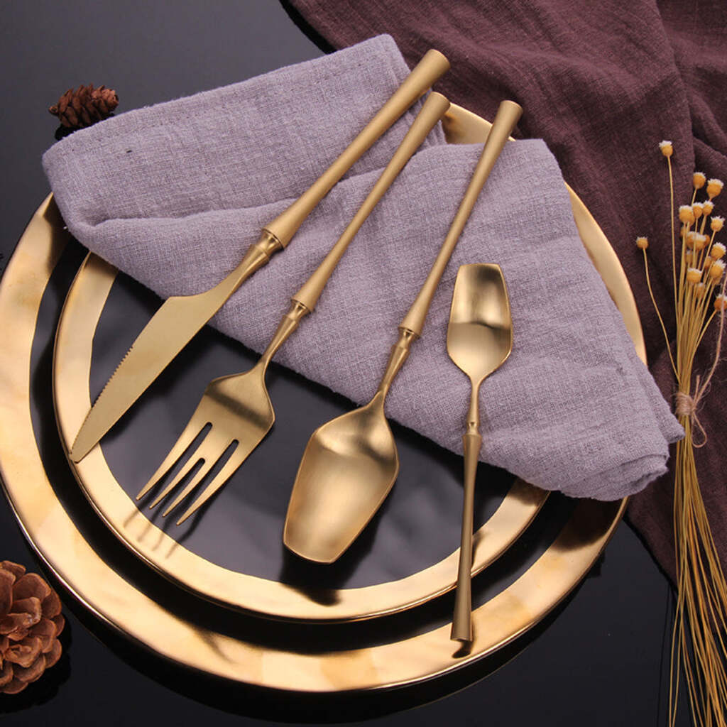 Gold cutlery set on a dark surface with a purple napkin