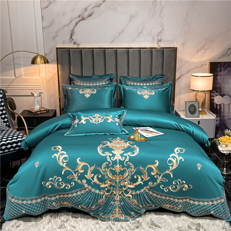Teal bedspread with gold embroidery on a bed in a bedroom setting.