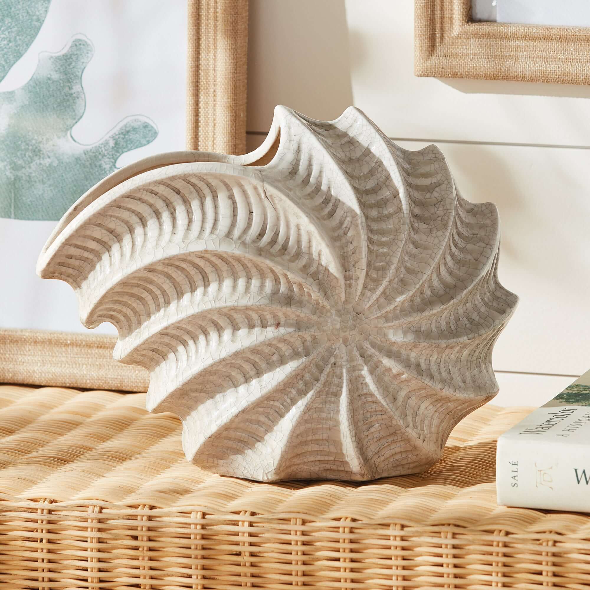 Decorative shell vase on a wicker surface with a blurred background