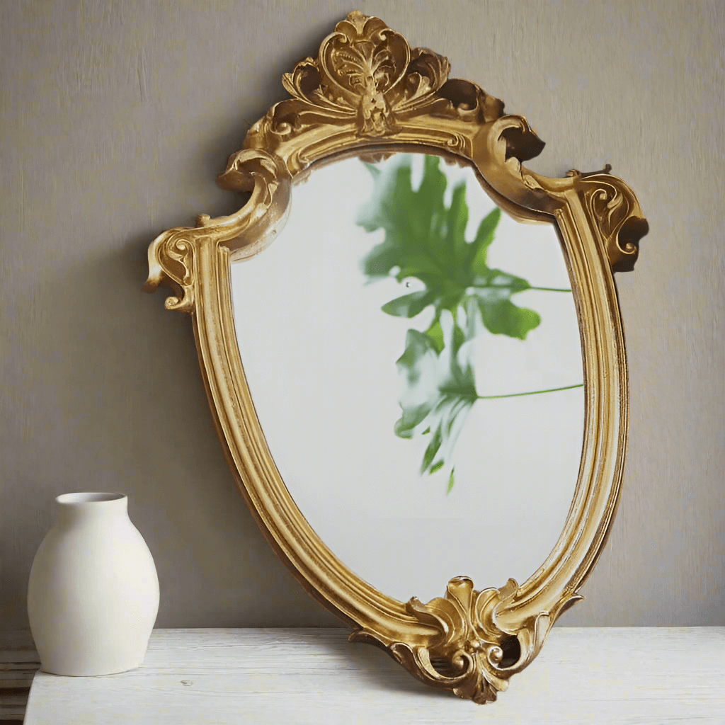 Decorative gold mirror with intricate designs on a neutral wall.