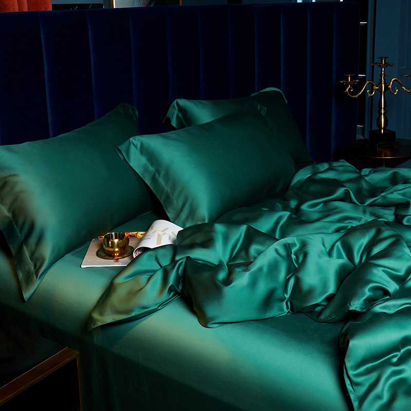 Teal satin bedding set on a bed with a dark headboard.
