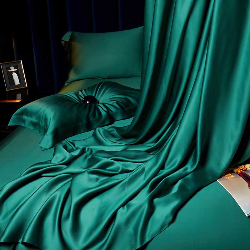 Teal satin bedding set on a bed with a dark background
