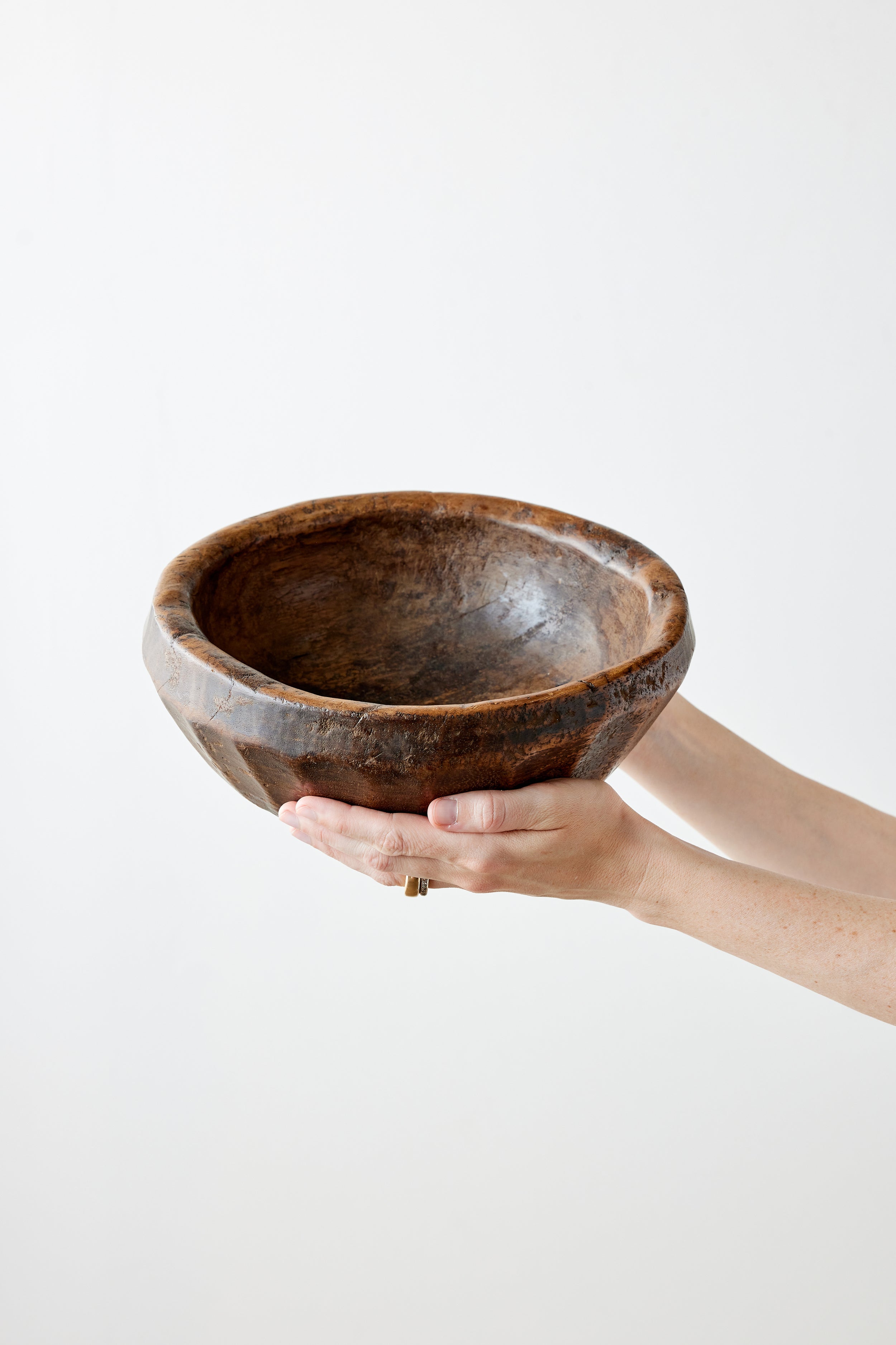 Hand holding a wooden bowl against a white background