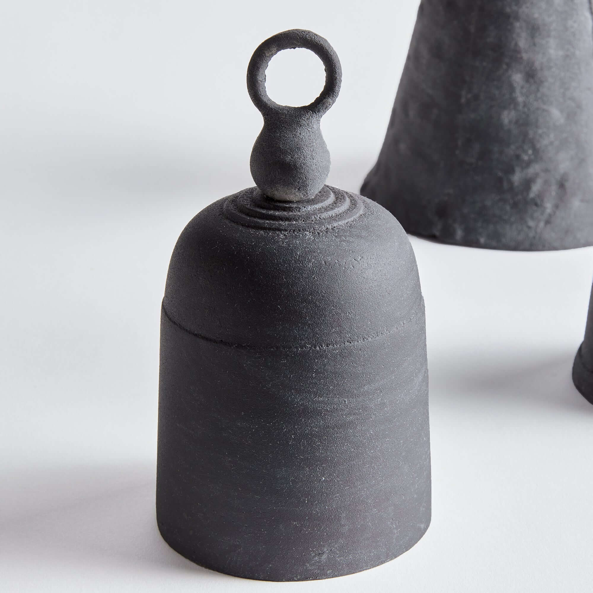 Black ceramic bell-shaped object on a white background