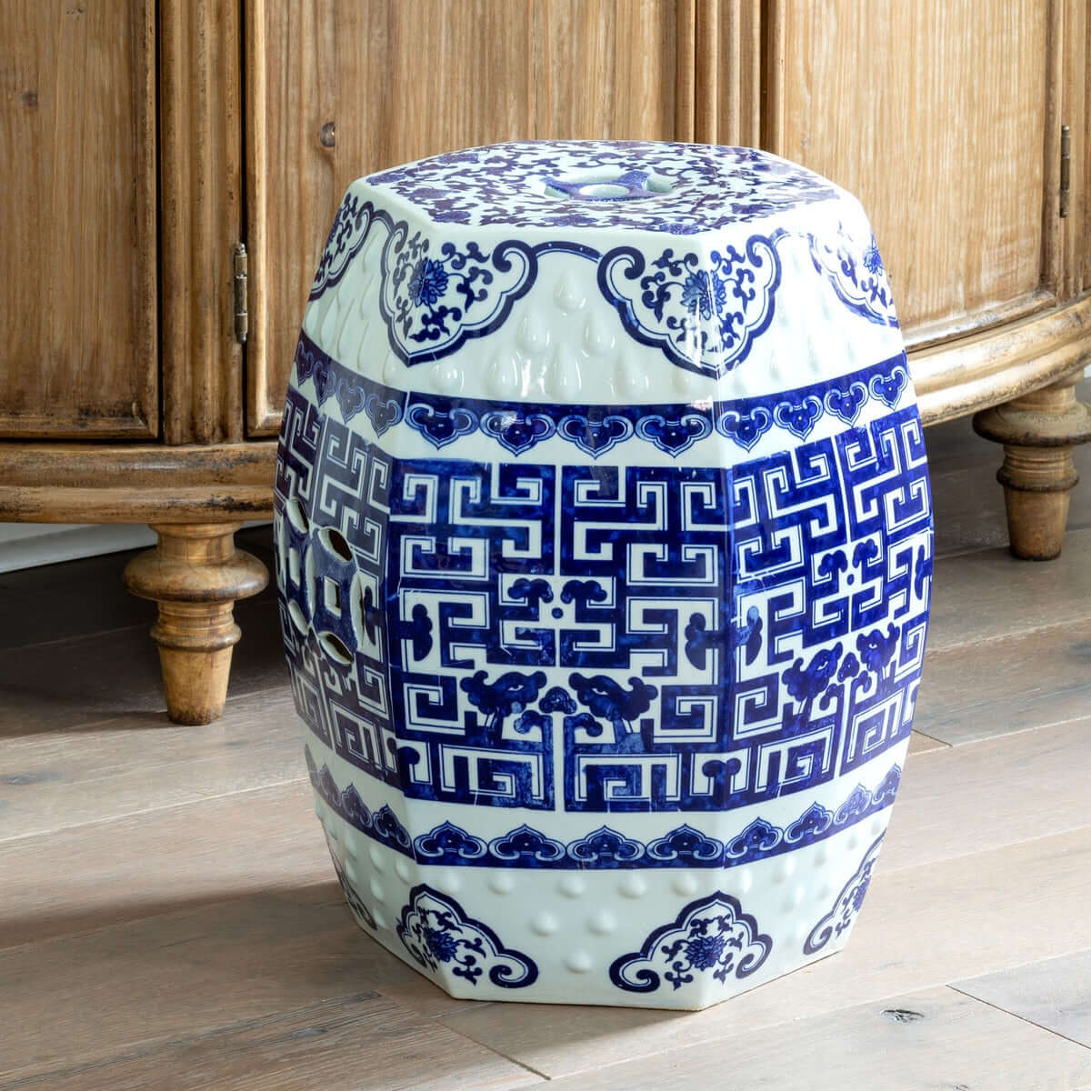 Decorative blue and white ceramic stool with intricate patterns in a room with wooden furniture.