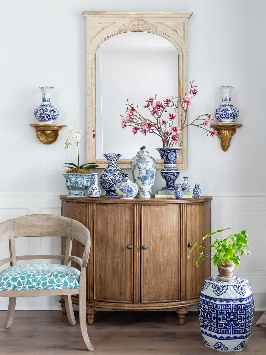 Wooden cabinet with decorative vases and a chair in a room setting.