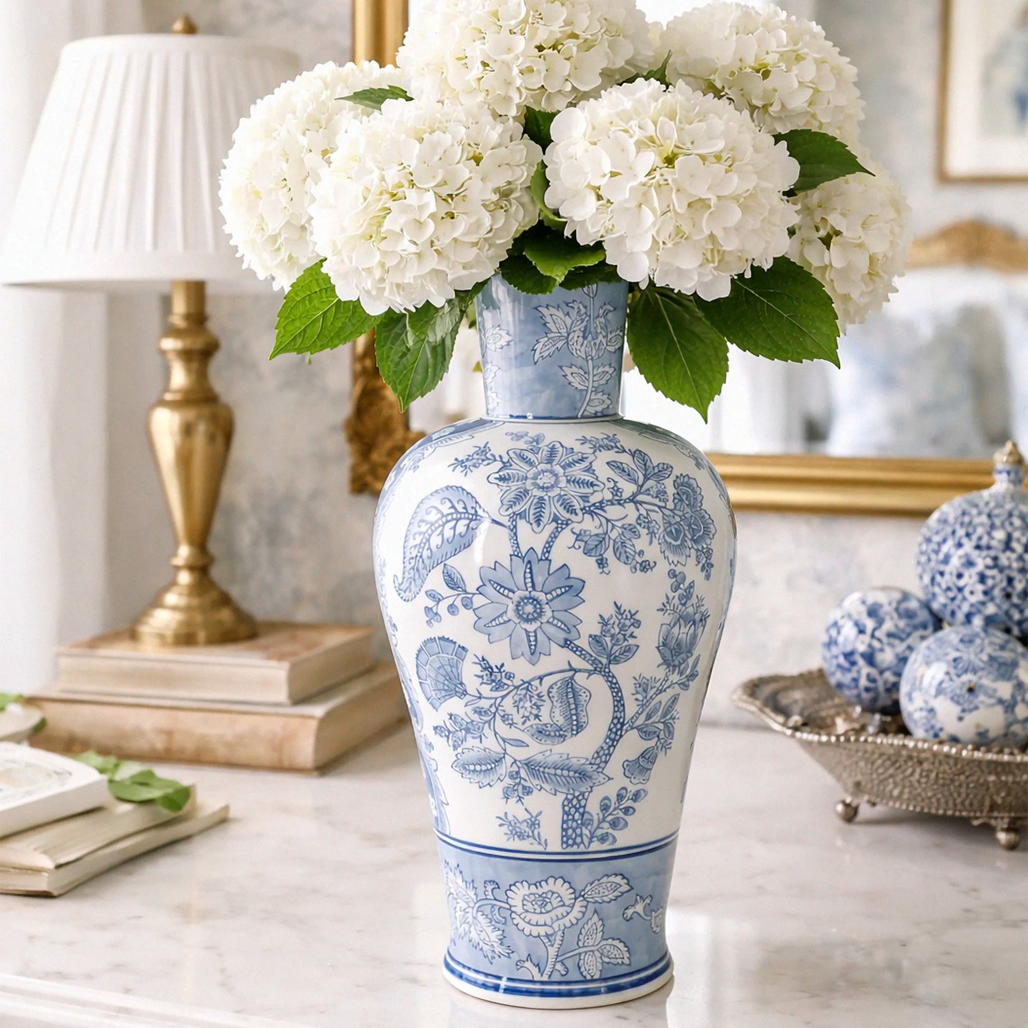 Blue and white floral-patterned vase with white flowers on a table with decorative accents