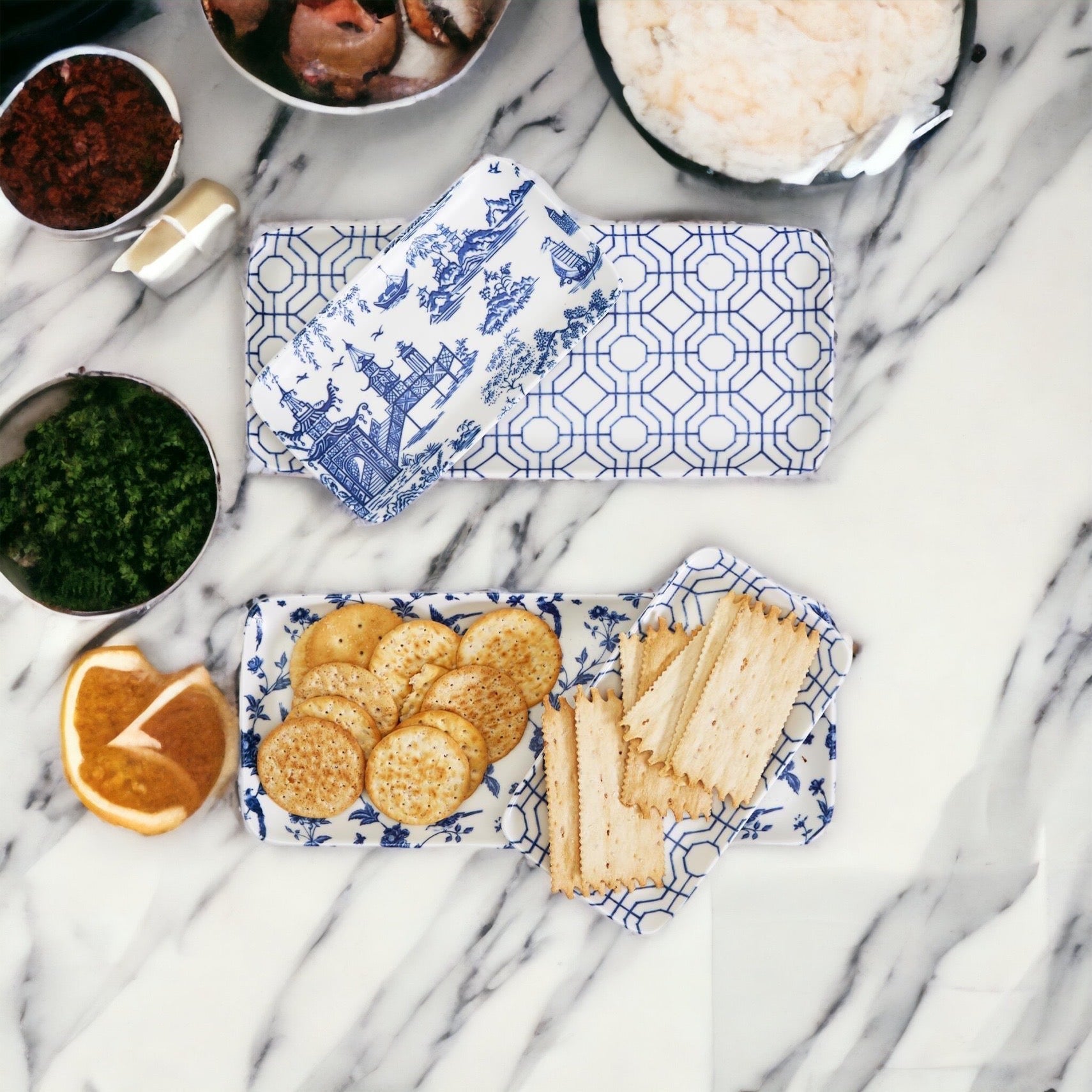 Rectangular blue and white patterned tray with cookies and crackers on a marble surface