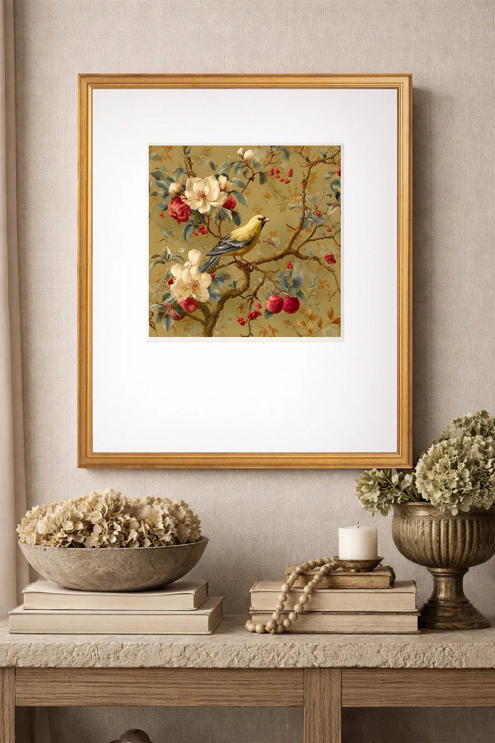 Framed gold Chinoiserie artwork of a bird on a branch with flowers and fruit, displayed on a wall above a console table.