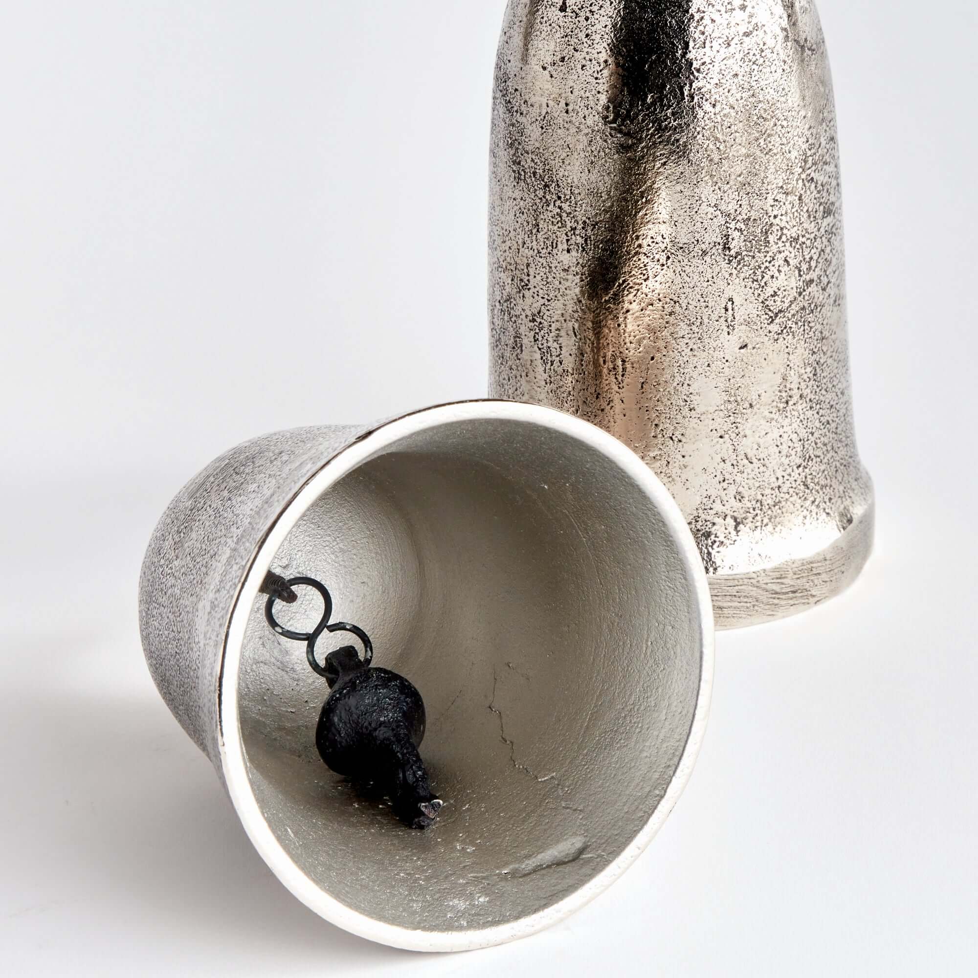 Two metallic cups, one with a black pendant inside, on a white background