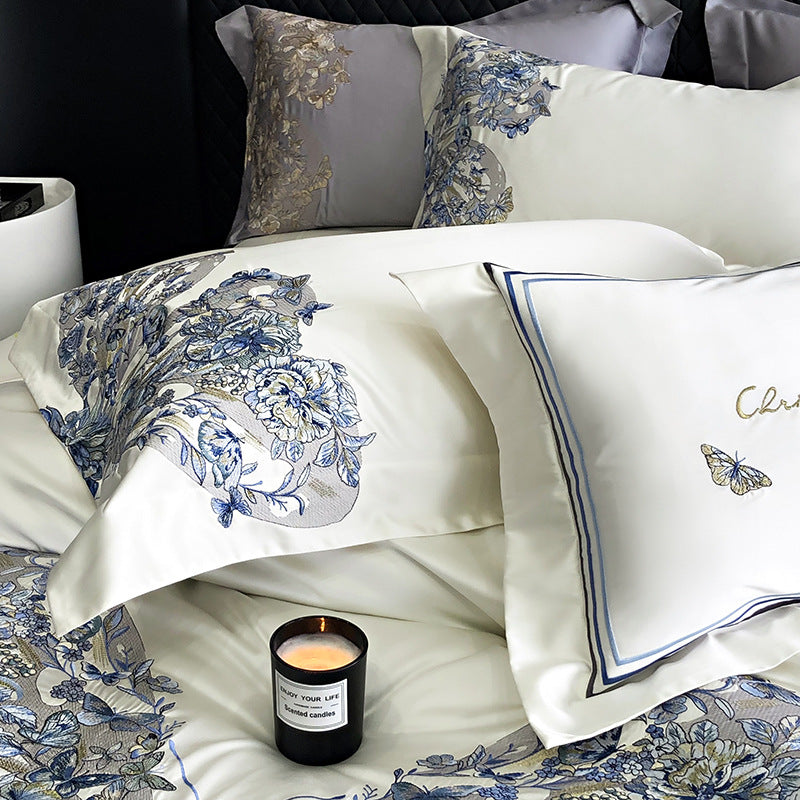 Decorative bedding set with floral patterns and a candle on a bed.