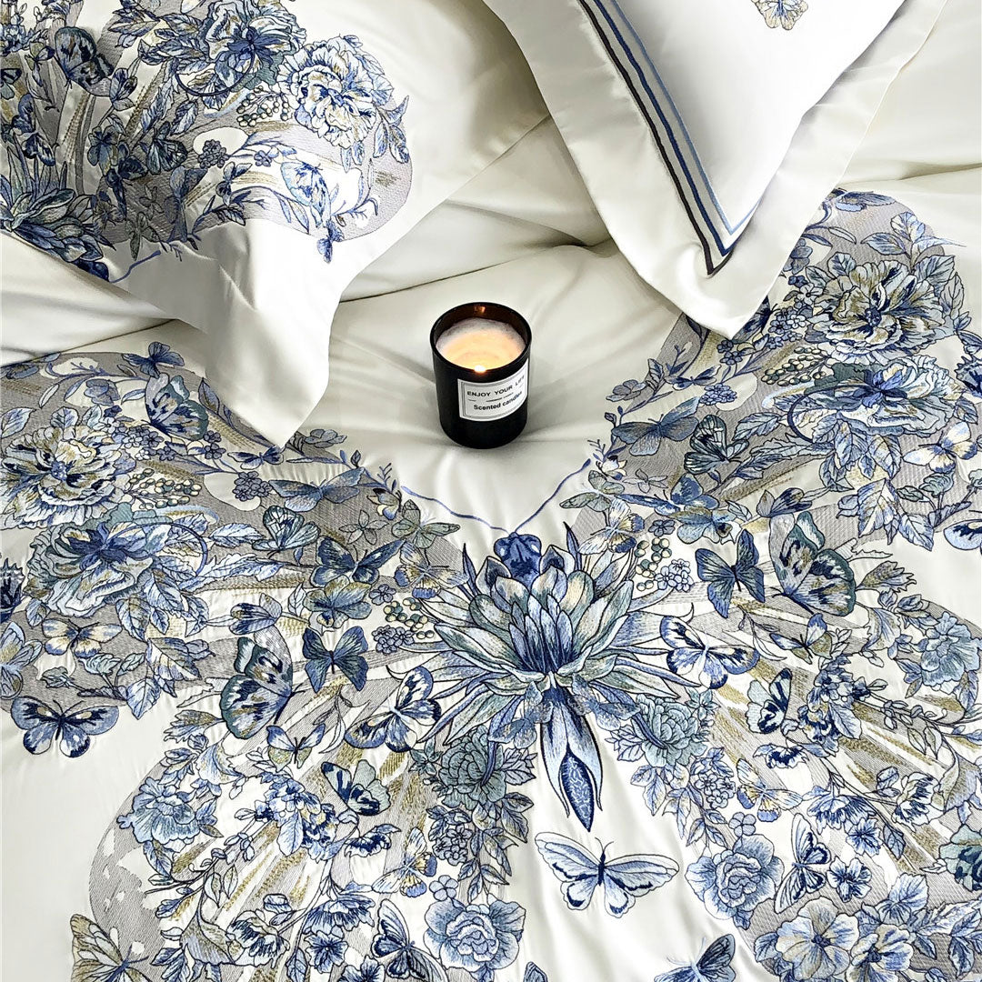 Close up of floral and butterfly patterned bedding with a candle on a white surface