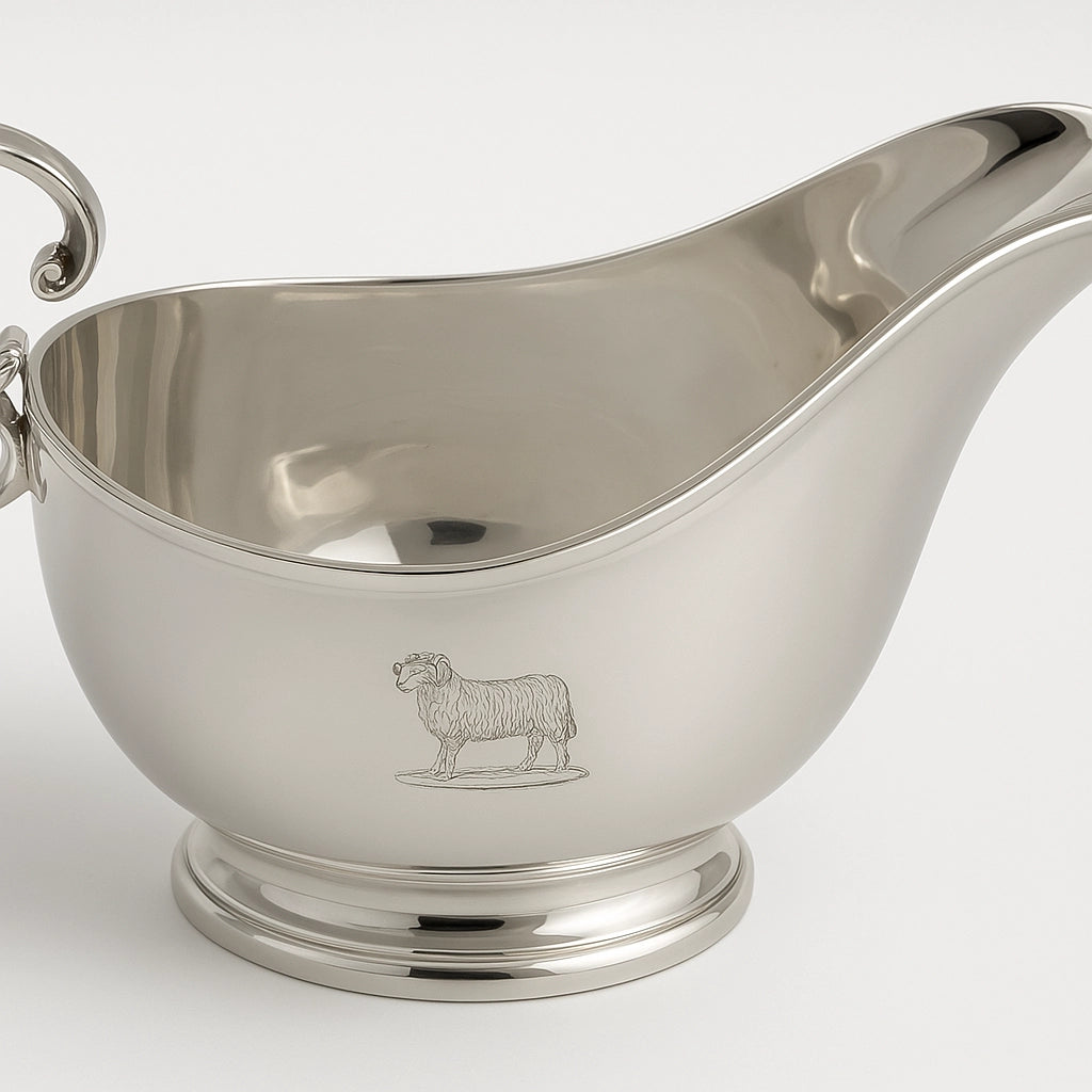 Close-up of English silver plate sauceboat featuring engraved crest-style motif on polished surface
