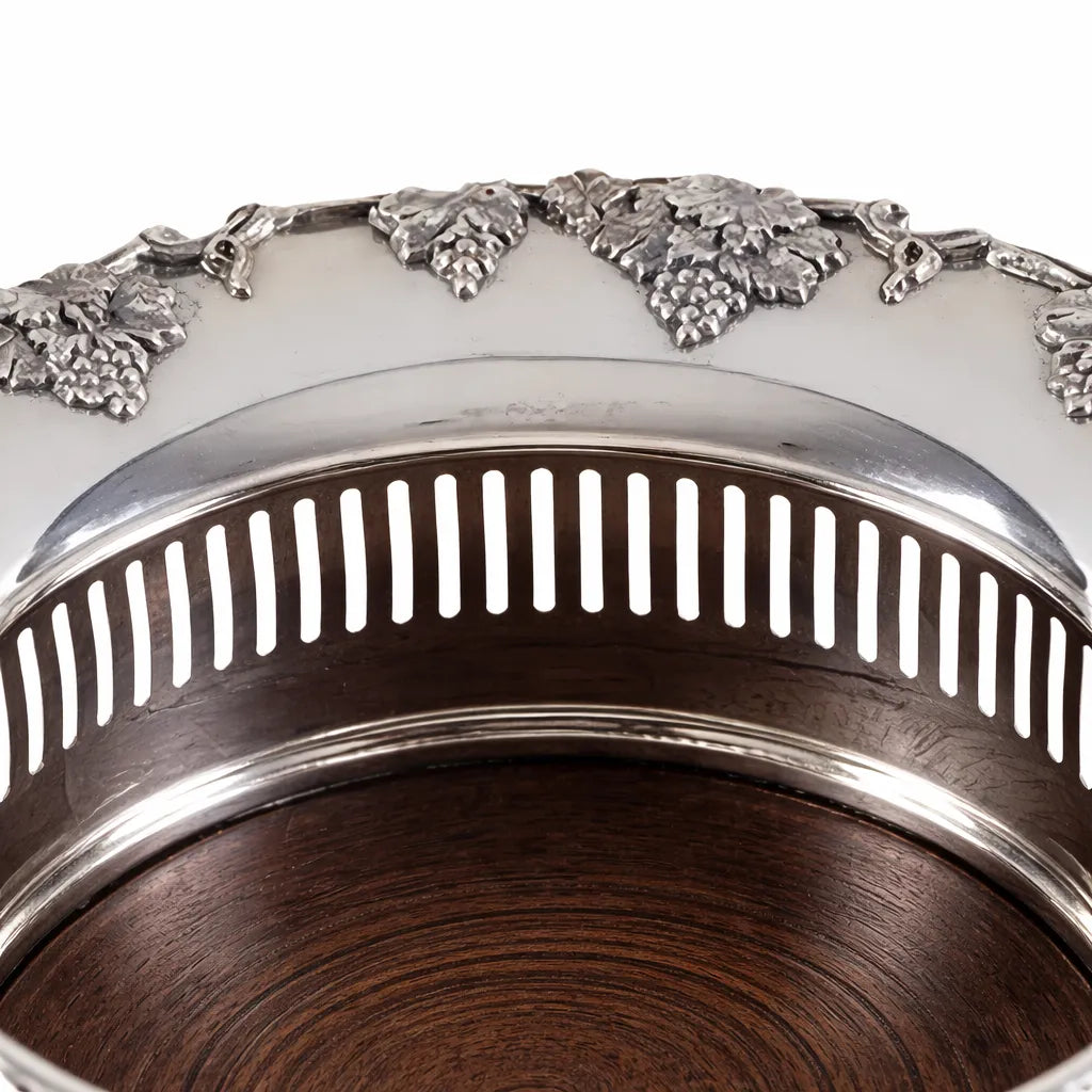 Close-up of English silver plate wine coaster with grape border and pierced gallery over wood base