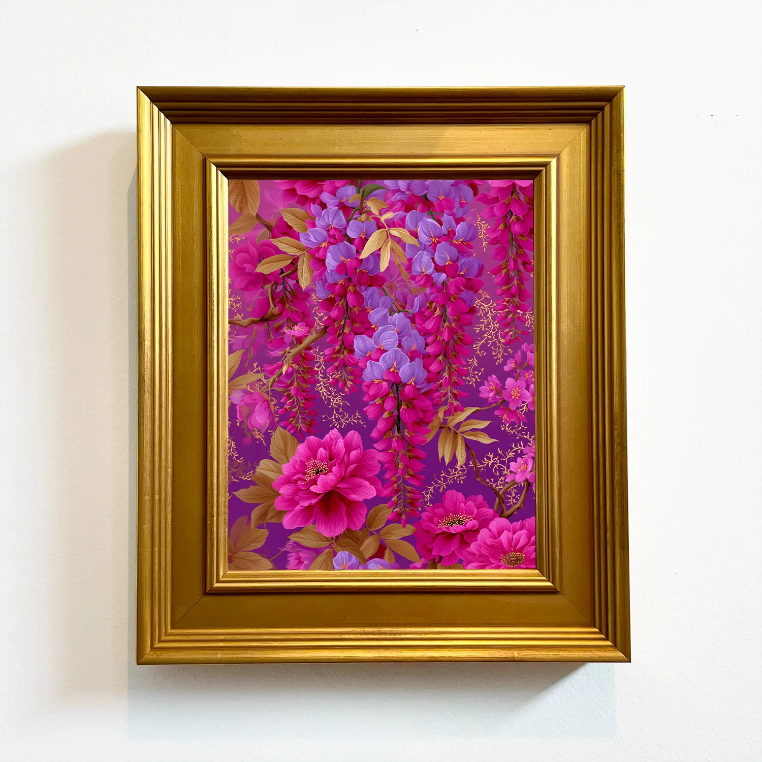 A framed floral art print featuring vibrant pink and purple wisteria flowers with green leaves, enclosed in a gold frame and mounted on a white wall.
