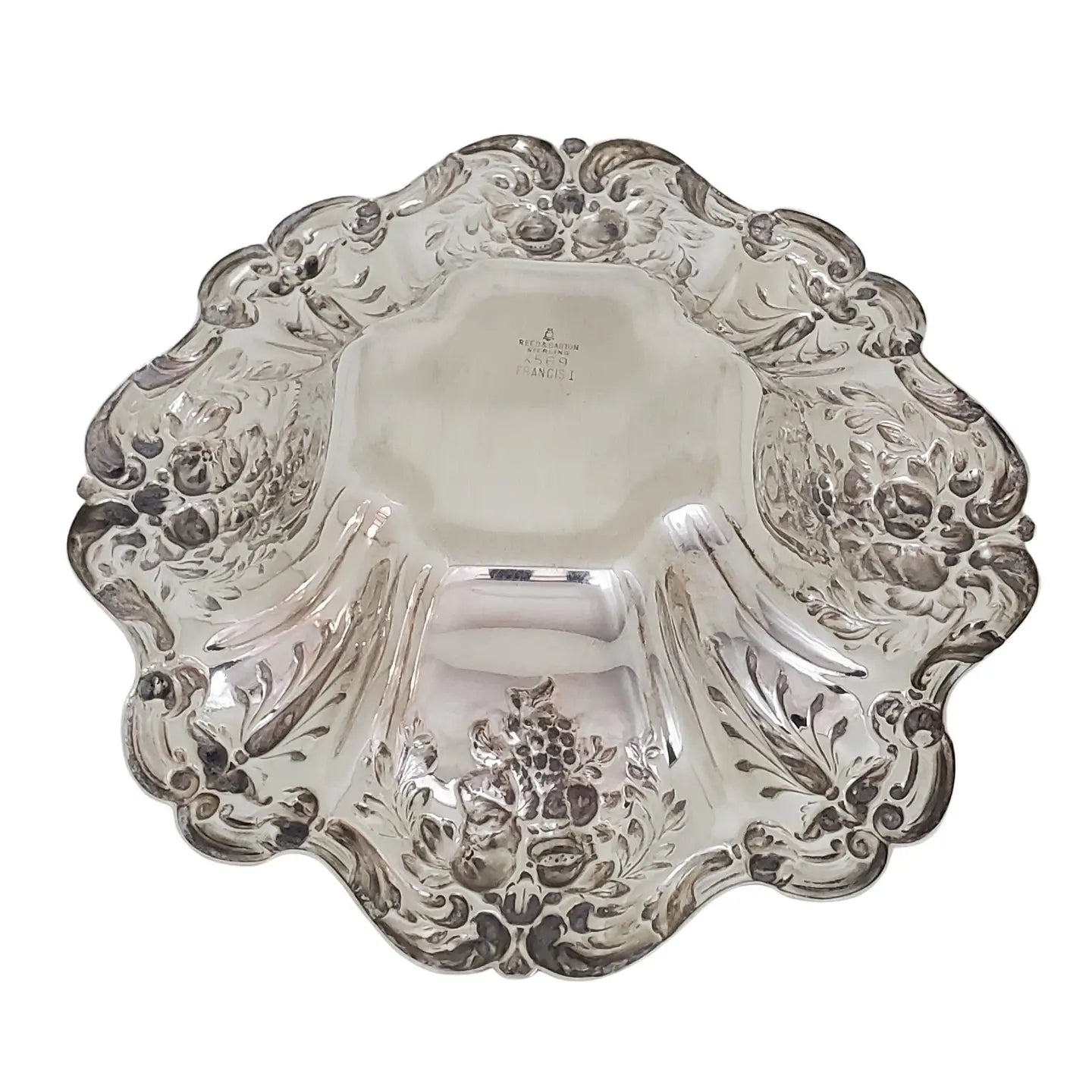 Underside of a Decorative silver bowl with intricate floral and fruit patterns on a white background