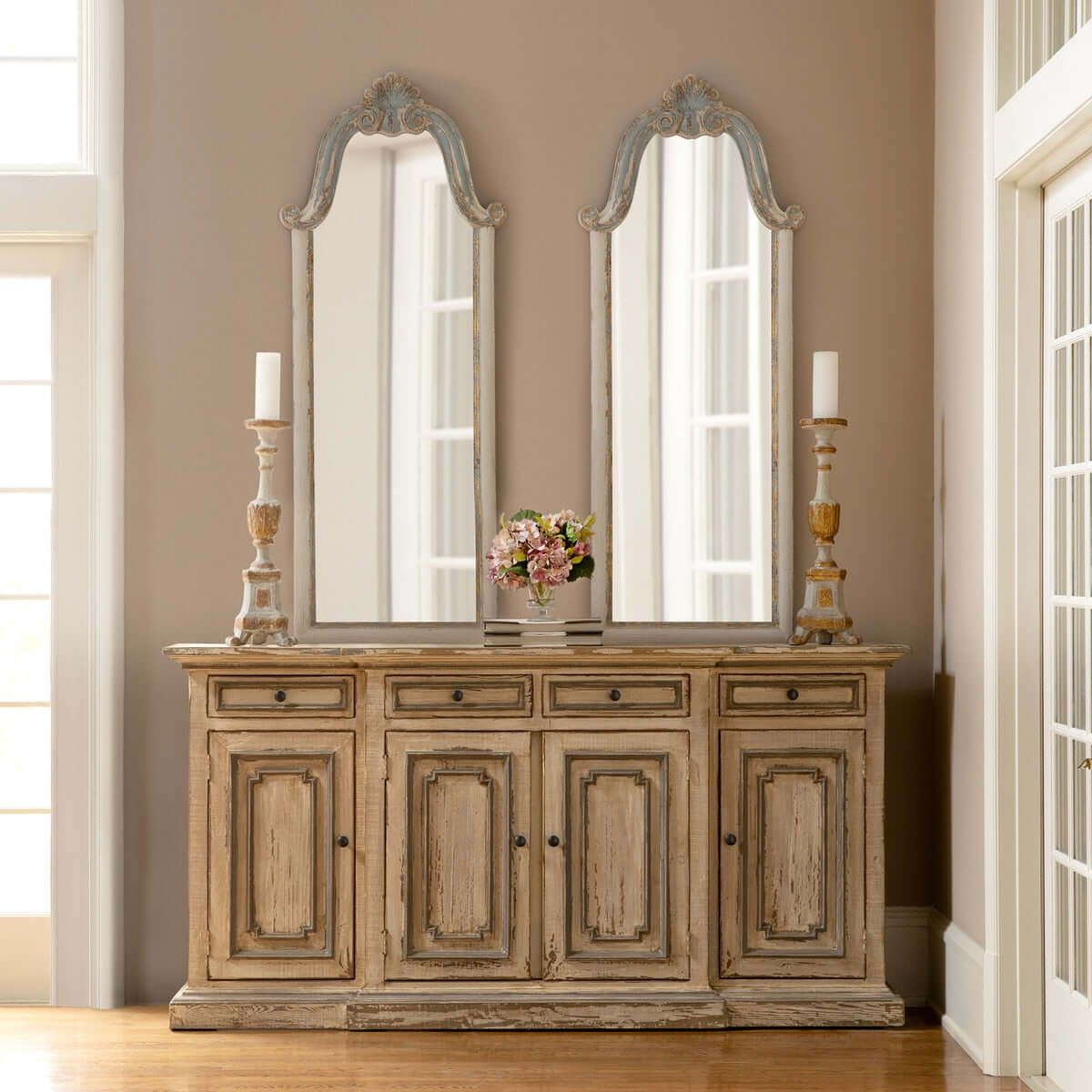 Wooden sideboard with two large mirrors and decorative items in a room.