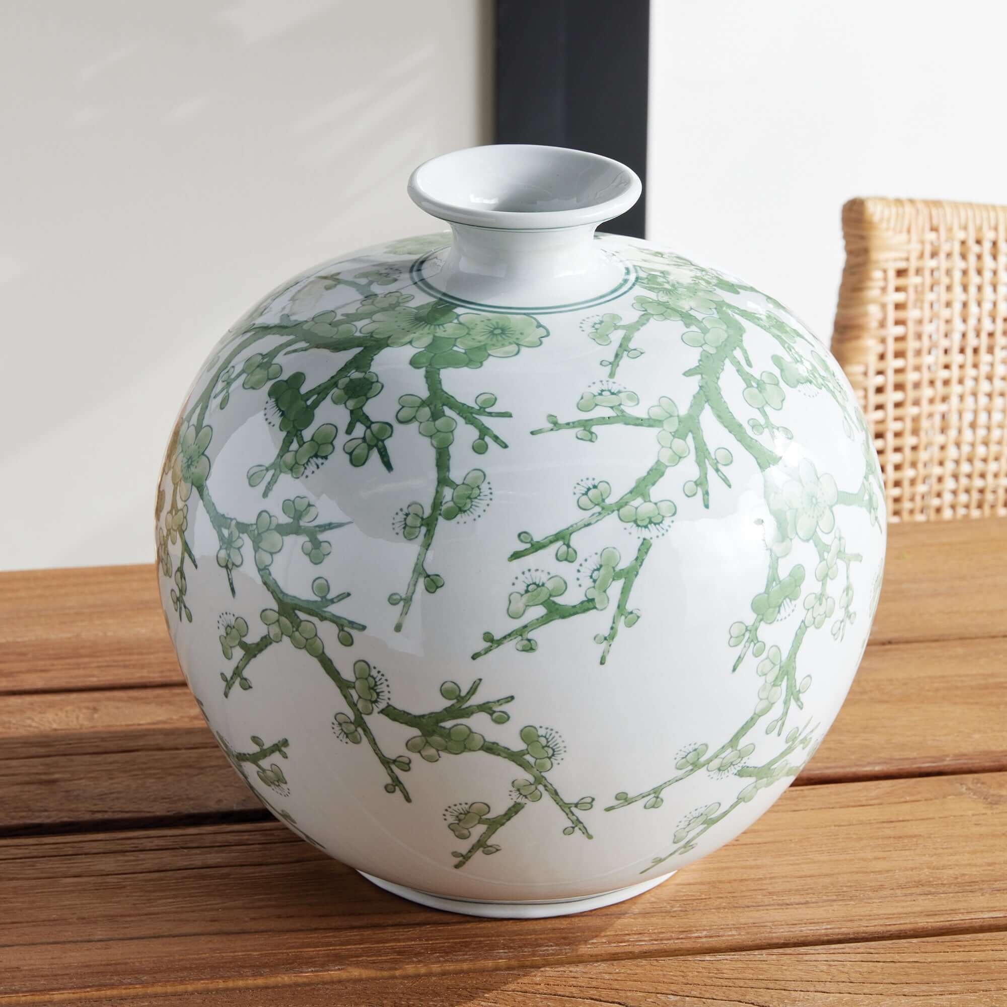 White vase with green floral patterns on a wooden surface