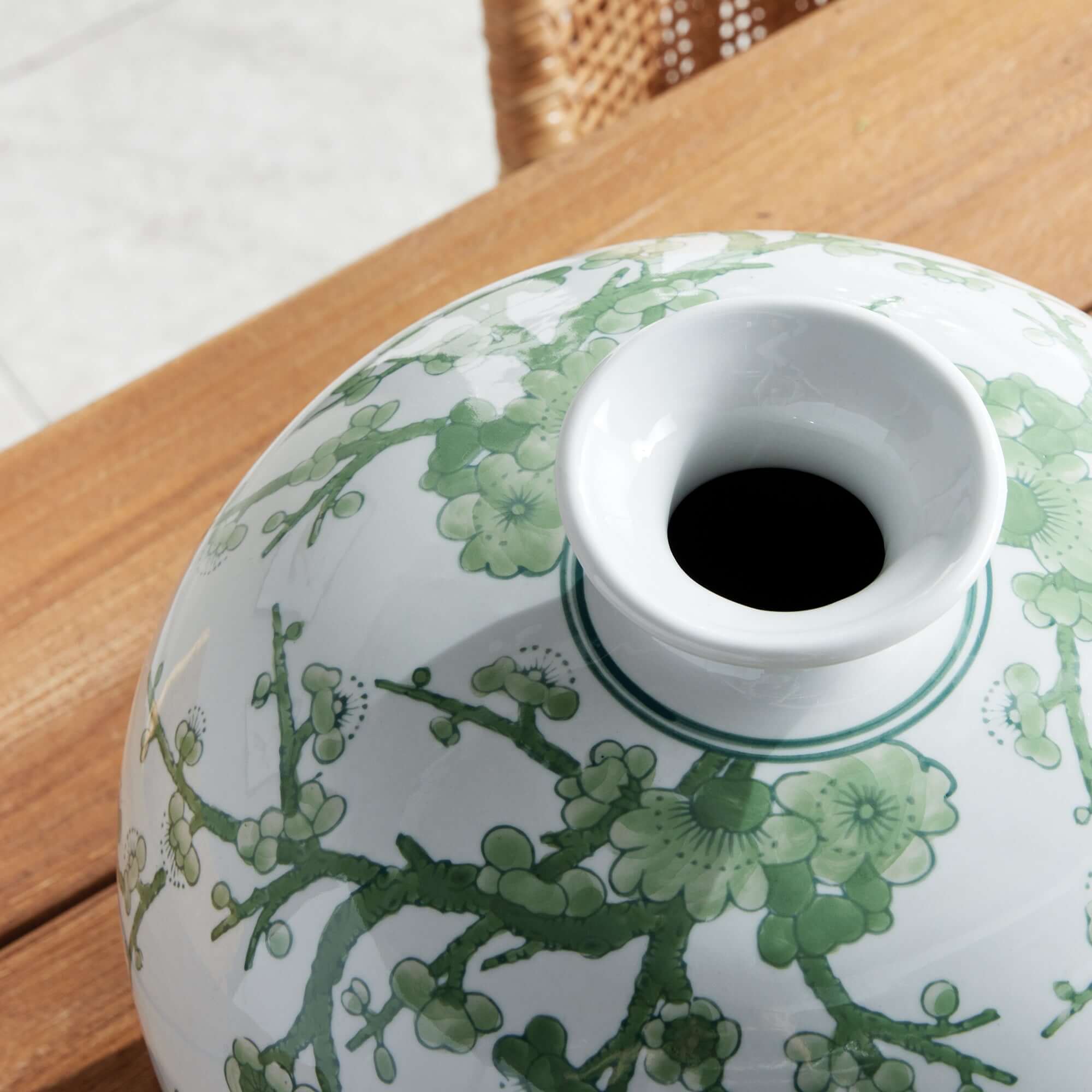 Ceramic vase with green floral design on a wooden surface
