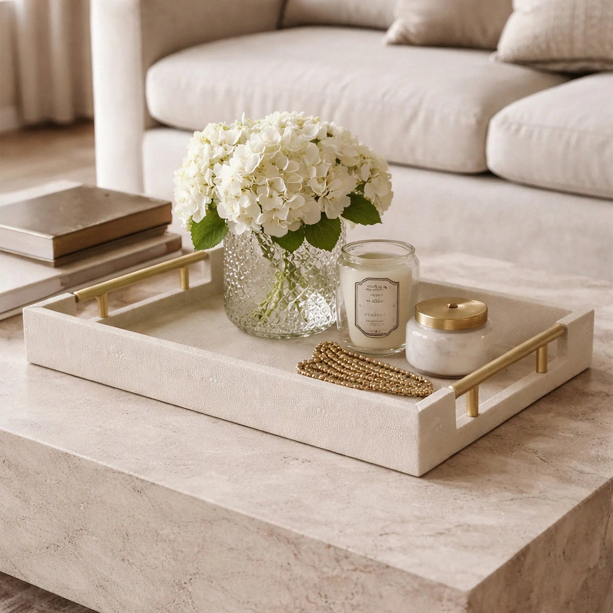 Decorative tray with flowers, candles, and jewelry on a coffee table in a living room.